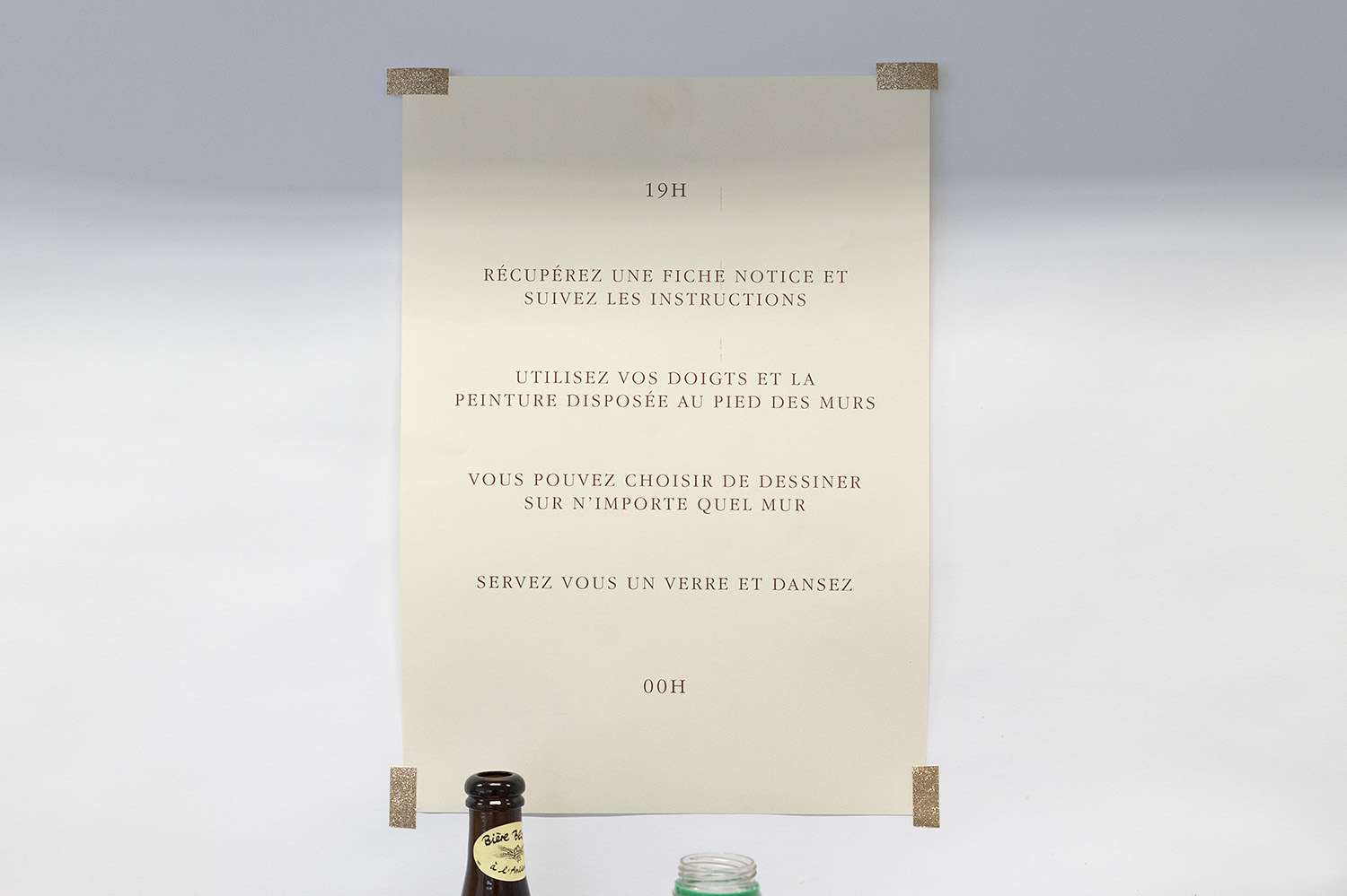 une affiche sur papier doré donne les instructions suivante : 19h, récupérez une fiche notice et suivez les insctructions, utilisez vos doigts et la peinture disposée au pied des murs, vous pouvez choisir de dessiner sur n'importe quel mur, servez-vous un verre et dansez, 00h.